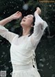 A woman in a white dress standing in the rain.