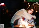 A woman sitting next to a fire pit at night.