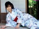 A woman in a blue and white kimono sitting on the ground.