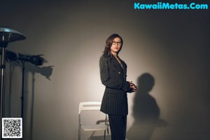 A woman standing in front of a white chair.
