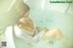 A woman sitting in a bathtub with her legs in the water.