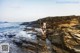 A woman sitting on a rock by the ocean.