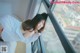 A woman leaning against a window looking out at the city.